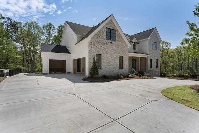 view of front of home with concrete driveway, fence, brick siding, and an attached garage