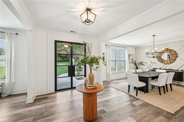 dining space featuring a chandelier, plenty of natural light, wood finished floors, crown molding, and baseboards