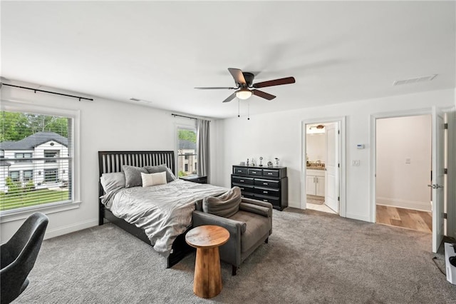 bedroom with carpet floors, multiple windows, baseboards, and ensuite bath