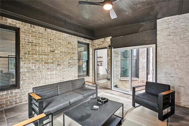 living area featuring a ceiling fan and brick wall