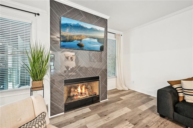 living room featuring crown molding, a fireplace, wood finished floors, and baseboards