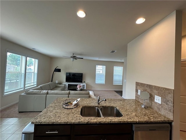 kitchen with light stone counters, stainless steel dishwasher, a healthy amount of sunlight, and sink