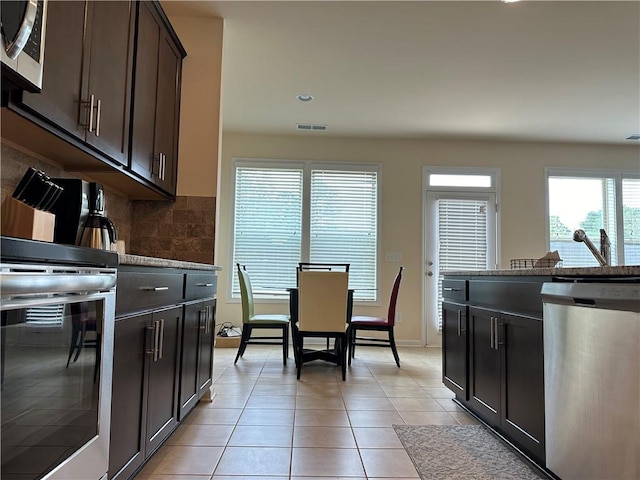 kitchen with appliances with stainless steel finishes, wine cooler, backsplash, light tile patterned floors, and dark brown cabinetry