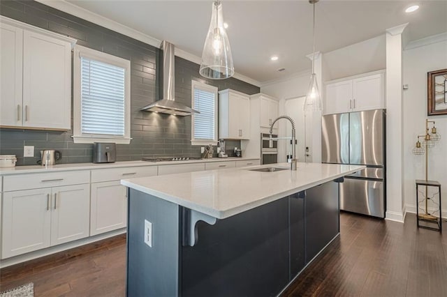 kitchen featuring ornamental molding, wall chimney exhaust hood, freestanding refrigerator, and a sink