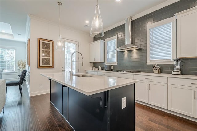 kitchen with ornamental molding, dark wood finished floors, white cabinetry, wall chimney exhaust hood, and stainless steel gas cooktop