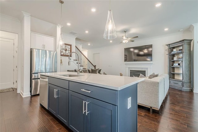 kitchen with ornamental molding, a sink, a glass covered fireplace, stainless steel appliances, and dark wood-style flooring