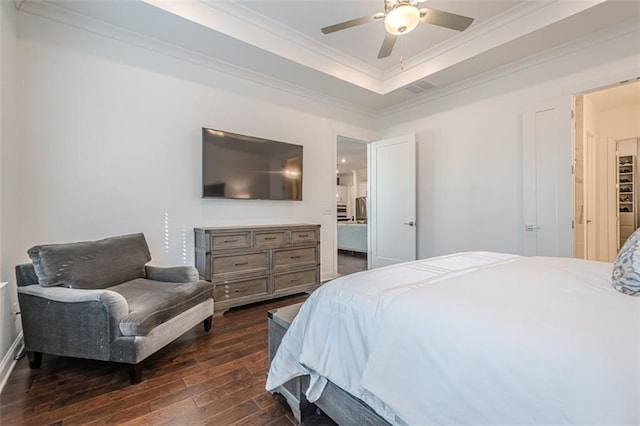 bedroom with a raised ceiling, a ceiling fan, dark wood-style flooring, and crown molding