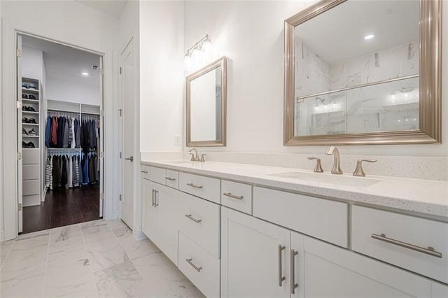bathroom with a marble finish shower, a spacious closet, double vanity, marble finish floor, and a sink