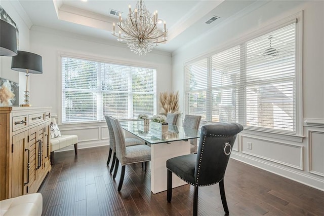dining space with a tray ceiling, visible vents, ornamental molding, and a decorative wall