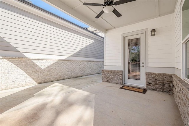 doorway to property with brick siding, ceiling fan, and a patio area