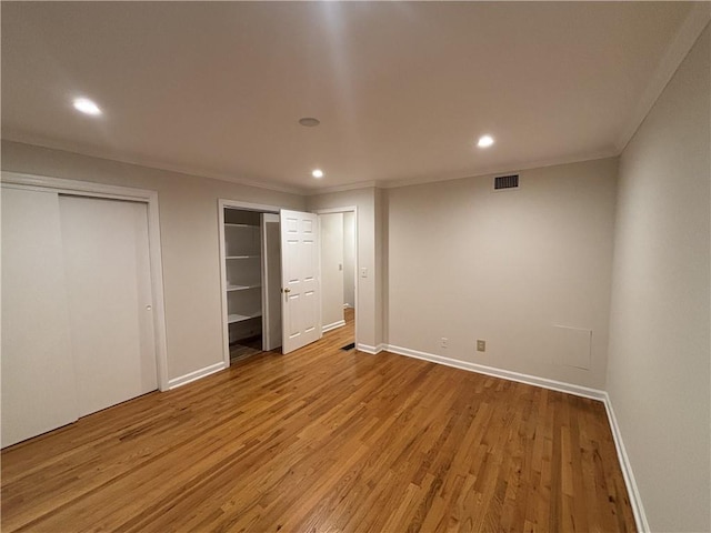 unfurnished bedroom featuring two closets, recessed lighting, light wood-style floors, baseboards, and ornamental molding