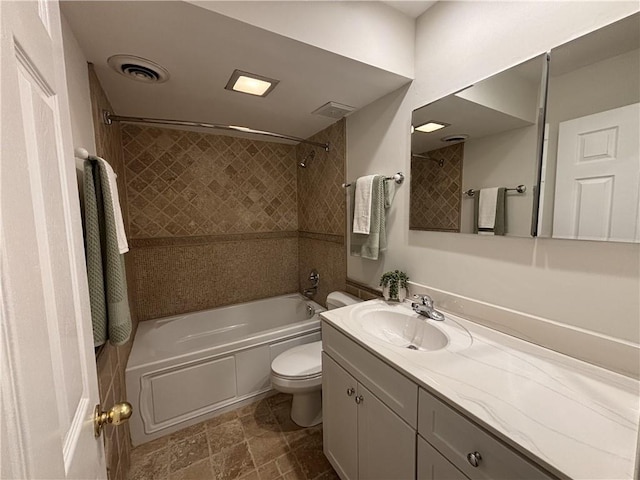 full bathroom with shower / bath combination, toilet, vanity, and stone finish floors
