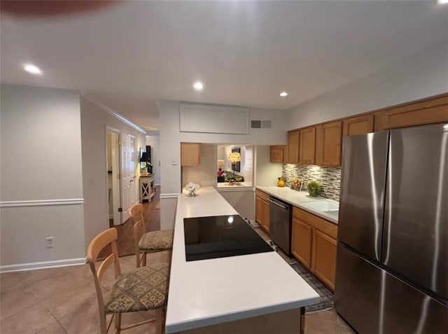 kitchen featuring stainless steel appliances, light countertops, brown cabinets, decorative backsplash, and recessed lighting