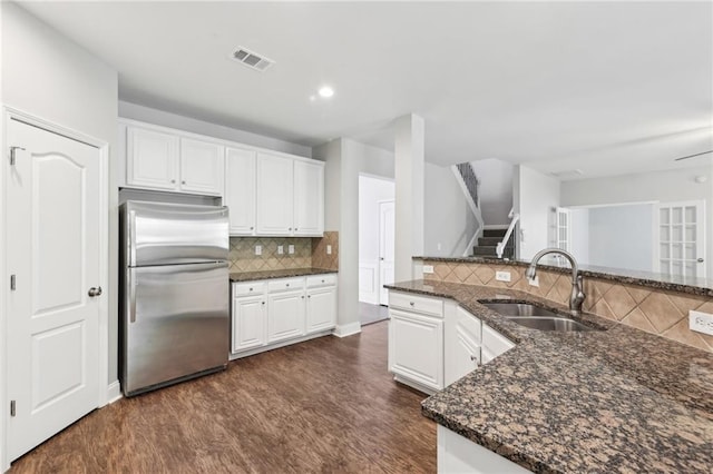 kitchen featuring dark wood-style floors, a sink, visible vents, freestanding refrigerator, and white cabinetry