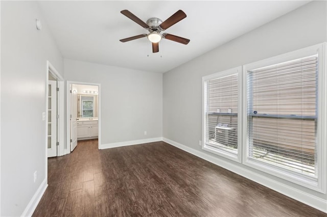 unfurnished bedroom with connected bathroom, a ceiling fan, baseboards, and dark wood-style flooring