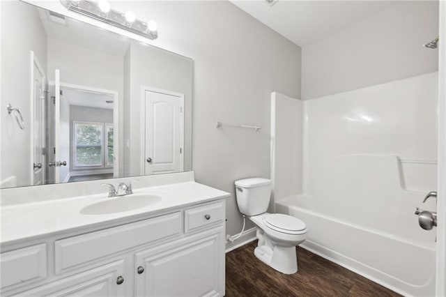 full bathroom with bathing tub / shower combination, toilet, baseboards, wood finished floors, and vanity