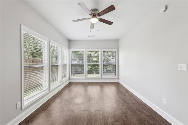 spare room with baseboards, a wealth of natural light, ceiling fan, and dark wood-style flooring