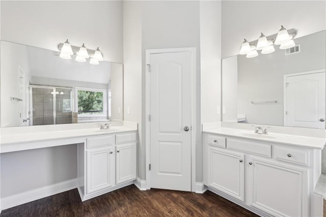 bathroom featuring a shower stall, wood finished floors, visible vents, a sink, and two vanities
