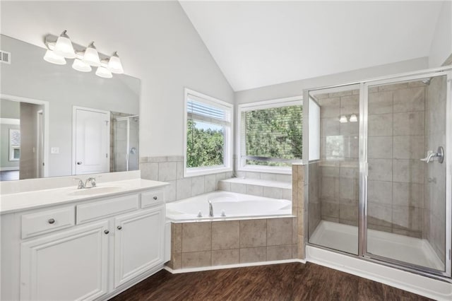 full bath with a shower stall, lofted ceiling, wood finished floors, vanity, and a garden tub