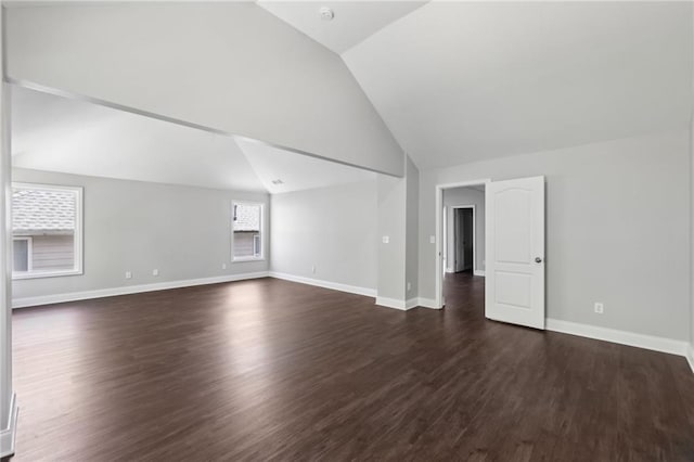 unfurnished living room featuring vaulted ceiling, baseboards, and dark wood-type flooring