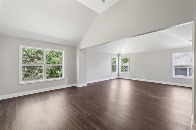 spare room featuring lofted ceiling, baseboards, and dark wood-style flooring