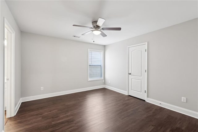 unfurnished room with dark wood-type flooring, visible vents, a ceiling fan, and baseboards