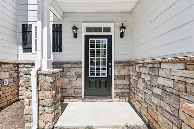 view of exterior entry with a porch and stone siding