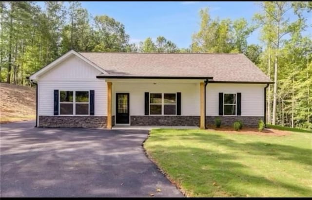 view of front facade with stone siding, a front lawn, and driveway