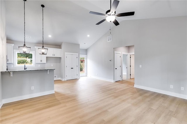 unfurnished living room with light wood finished floors, ceiling fan, visible vents, and a wealth of natural light