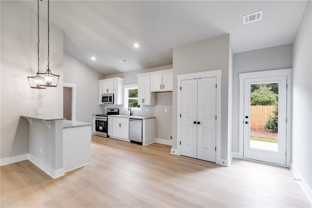 kitchen with stainless steel appliances, a peninsula, visible vents, white cabinetry, and light wood-type flooring