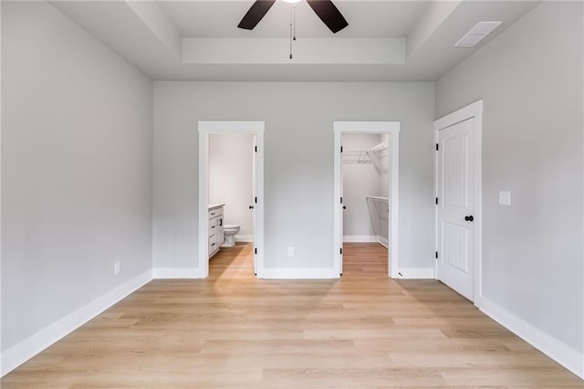 unfurnished bedroom with light wood-style flooring, visible vents, and a raised ceiling