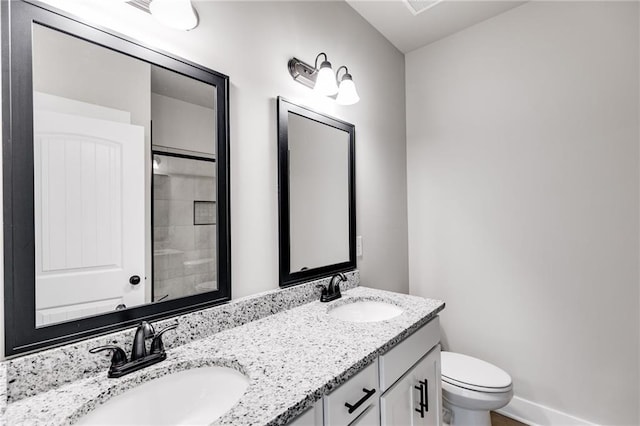 full bathroom featuring double vanity, a sink, toilet, and baseboards