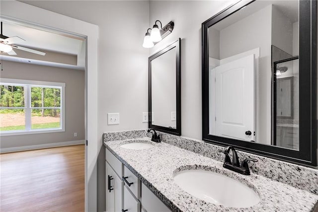 bathroom featuring double vanity, wood finished floors, a sink, and a shower with door