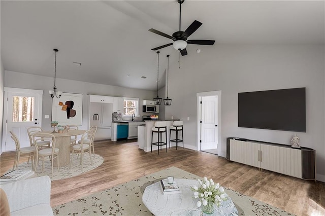 living room featuring ceiling fan, high vaulted ceiling, wood finished floors, and baseboards