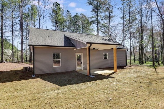 rear view of house featuring a shingled roof, cooling unit, a patio area, and a yard