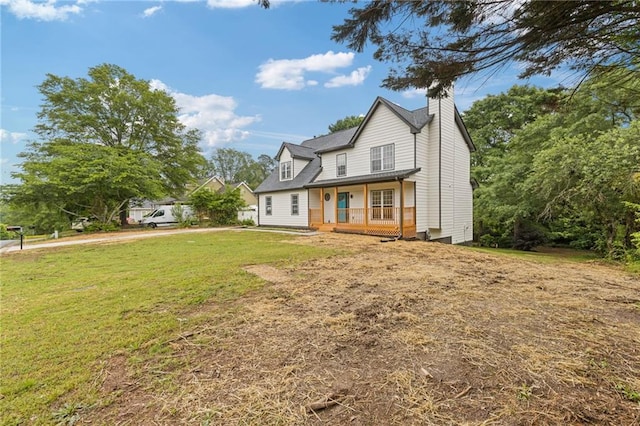 rear view of property with covered porch, a lawn, and a chimney