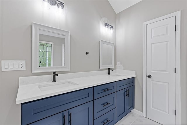 full bath with double vanity, a sink, marble finish floor, and baseboards