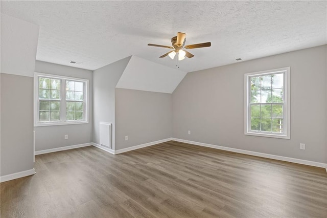 bonus room featuring visible vents, wood finished floors, baseboards, ceiling fan, and a textured ceiling