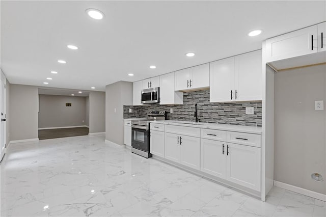 kitchen with a sink, light countertops, marble finish floor, stainless steel appliances, and baseboards