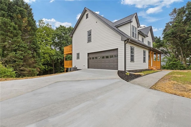 view of side of property with a porch, a garage, and concrete driveway
