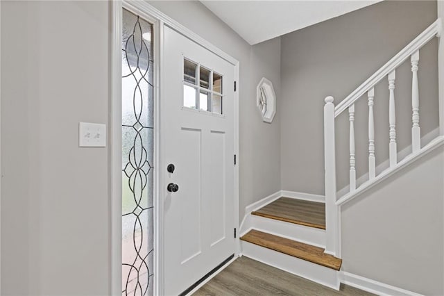 foyer featuring baseboards, stairs, and wood finished floors