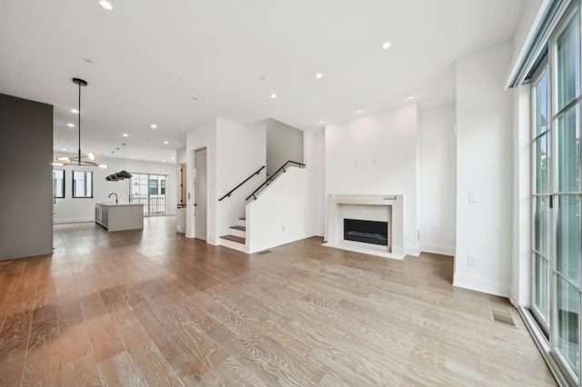71 Krog St NE, Atlanta, GA 30307 - unfurnished living room with light wood-style floors, a fireplace with flush hearth, a sink, stairs, and recessed lighting