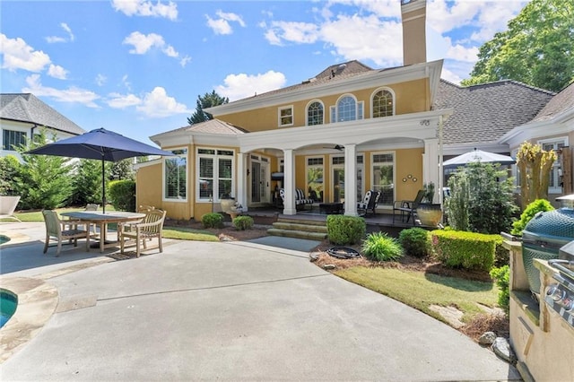 back of property with outdoor dining space, stucco siding, a patio, and a chimney