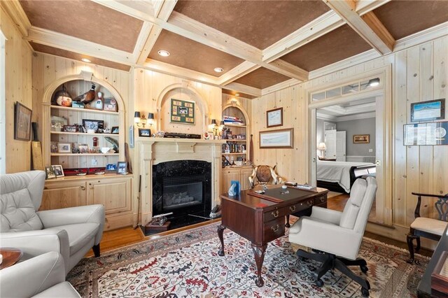 office area with coffered ceiling, crown molding, wooden walls, and built in shelves