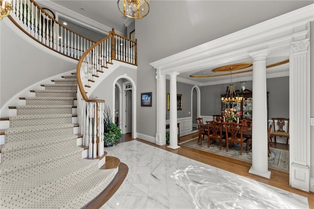 entrance foyer featuring arched walkways, stairway, a notable chandelier, and crown molding