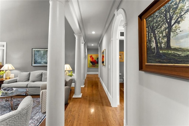 corridor featuring baseboards, recessed lighting, crown molding, decorative columns, and wood finished floors