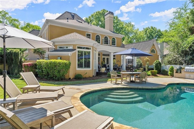 back of property with an outdoor pool, a chimney, and a patio area