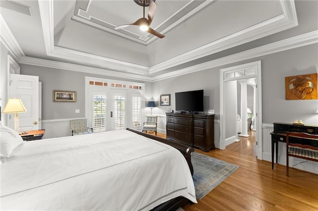 bedroom with crown molding, a tray ceiling, access to outside, and wood finished floors