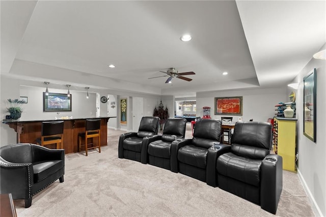 cinema featuring ceiling fan, light colored carpet, indoor bar, and a raised ceiling