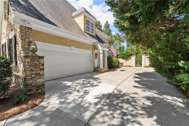 view of property exterior with stucco siding, stone siding, a shingled roof, and concrete driveway